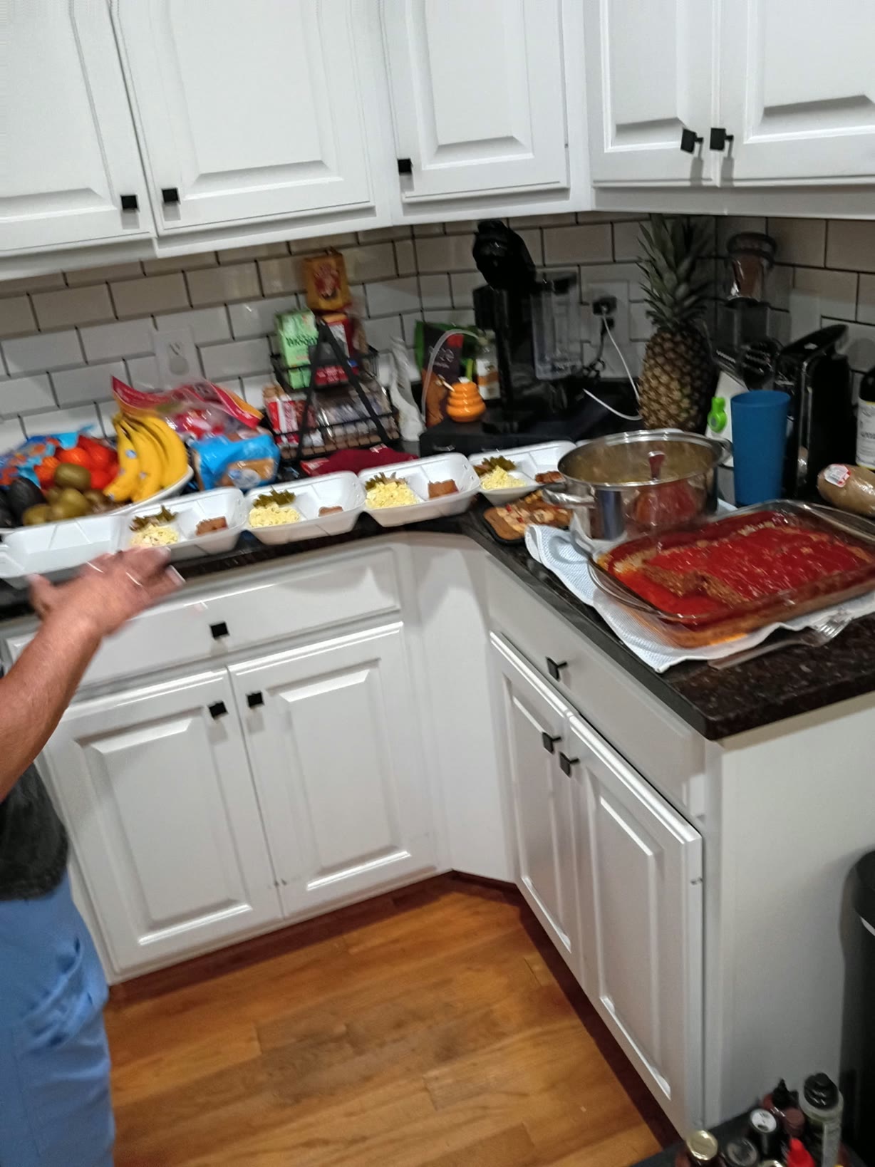 Kitchen counters holding food and a row of meal containers being prepared